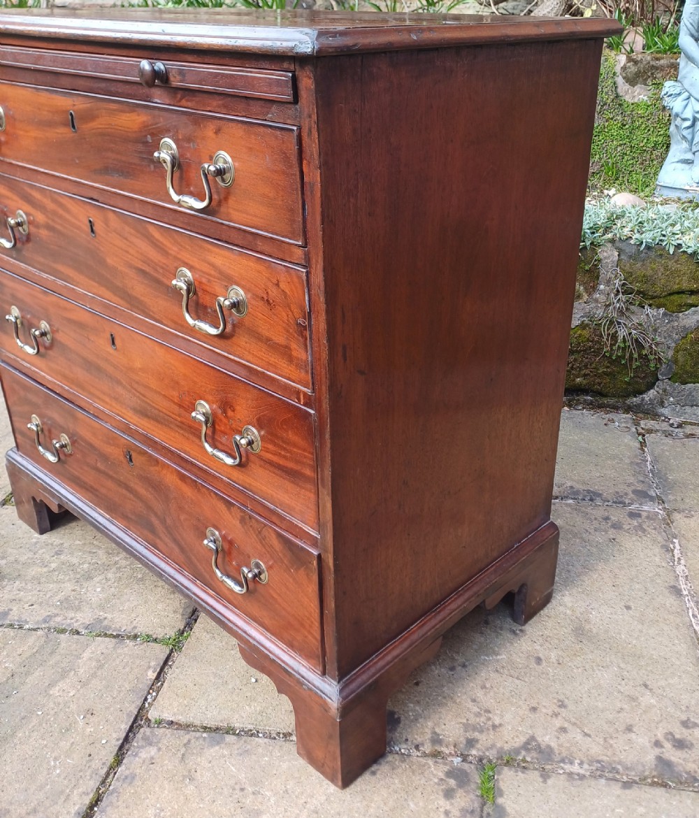 A small Georgian mahogany chest of drawers featuring four graduated drawers, brass swan-neck handles, a pull-out brushing slide, and bracket feet. View X