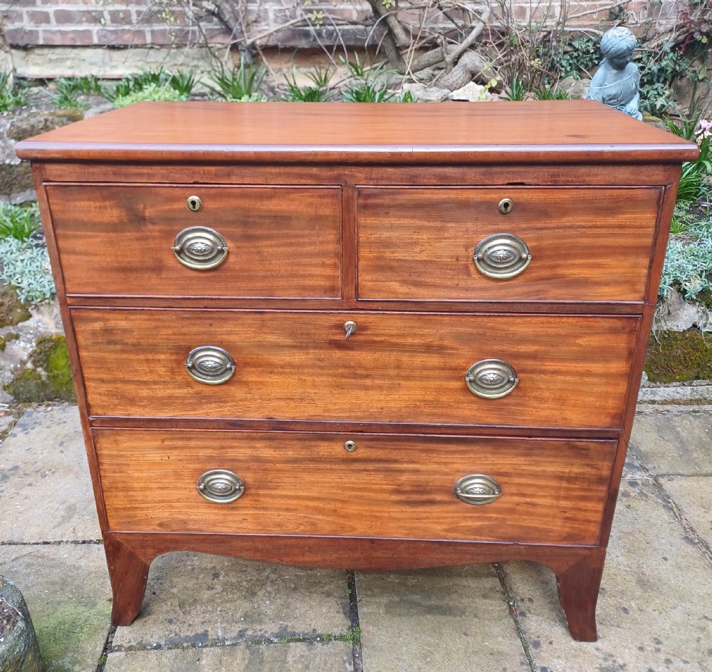 A small Regency mahogany chest of drawers with two short drawers over two long drawers, fitted with brass oval handles and supported on splayed bracket feet.