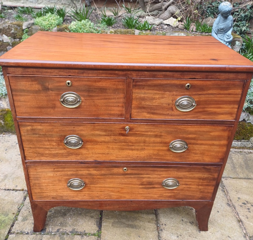 A small Regency mahogany chest of drawers with two short drawers over two long drawers, fitted with brass oval handles and supported on splayed bracket feet. View II