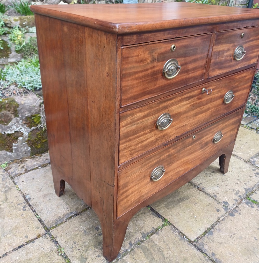 A small Regency mahogany chest of drawers with two short drawers over two long drawers, fitted with brass oval handles and supported on splayed bracket feet. View V