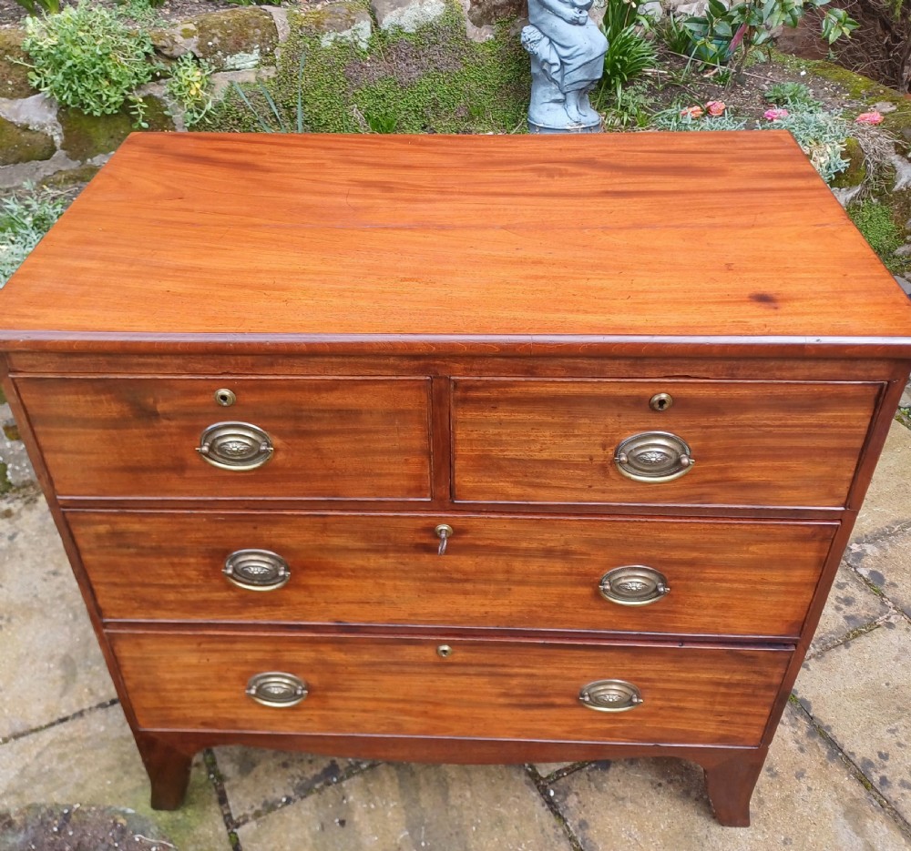 A small Regency mahogany chest of drawers with two short drawers over two long drawers, fitted with brass oval handles and supported on splayed bracket feet. View X