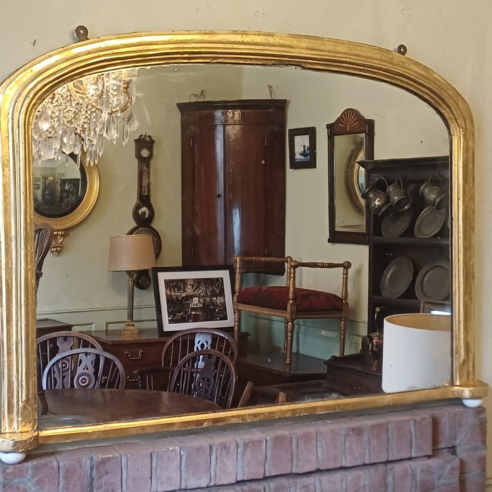 A Victorian giltwood overmantel mirror featuring an arched top frame and moulded gold finish. View III