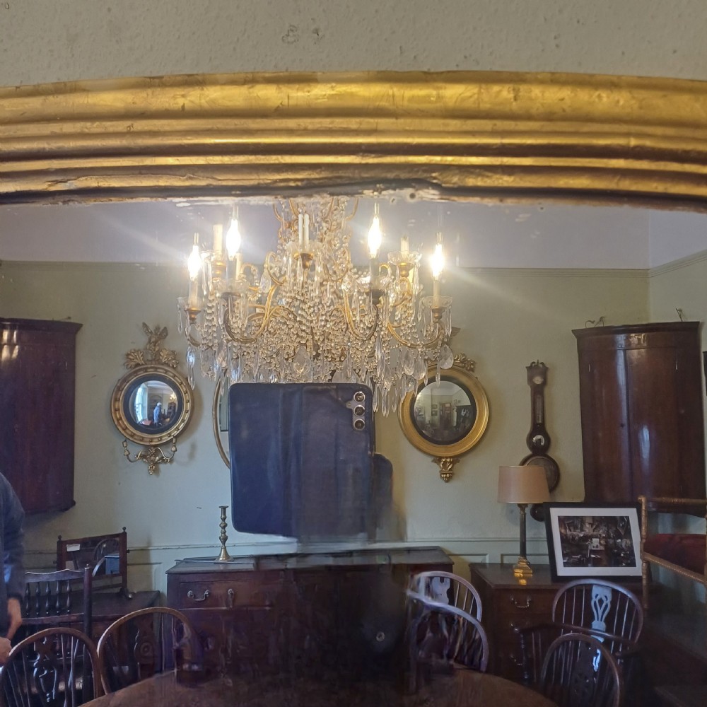 A Victorian giltwood overmantel mirror featuring an arched top frame and moulded gold finish. View IV