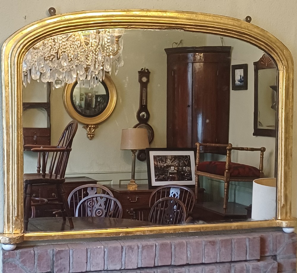A Victorian giltwood overmantel mirror featuring an arched top frame and moulded gold finish. View V