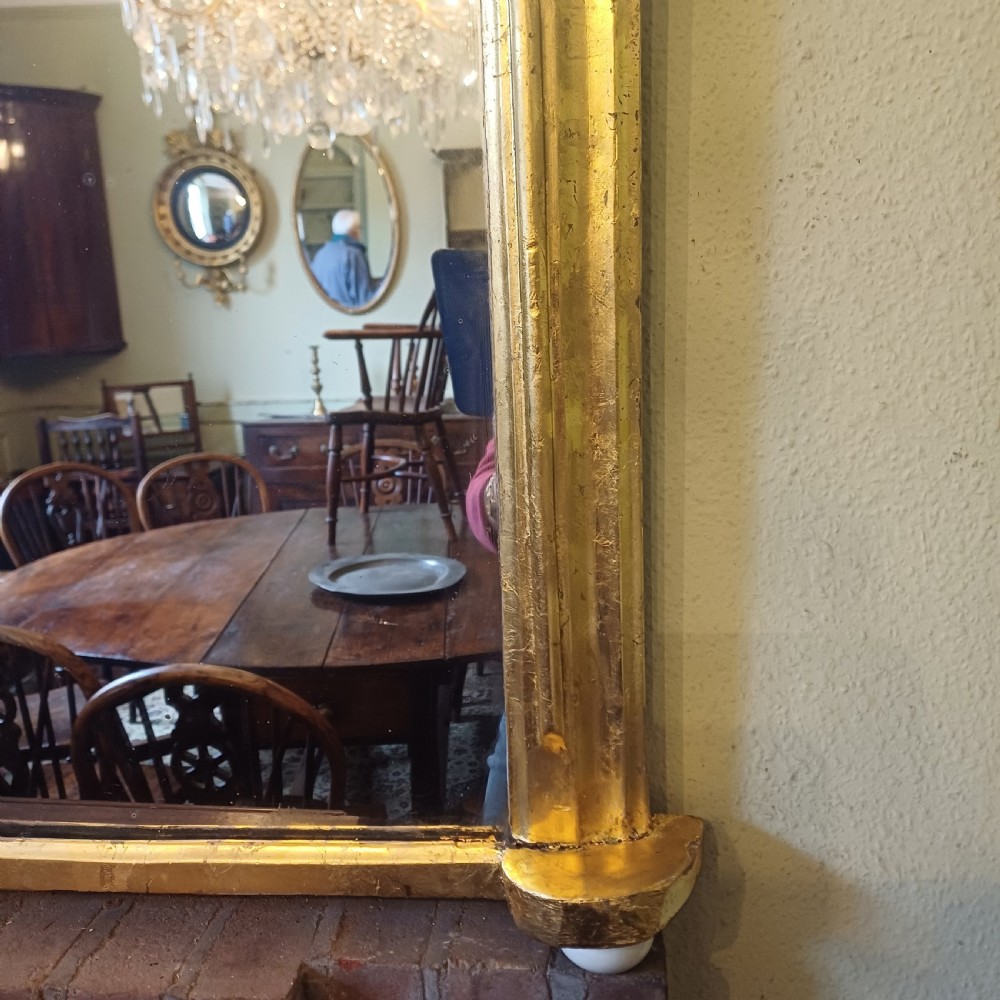 A Victorian giltwood overmantel mirror featuring an arched top frame and moulded gold finish. View VII