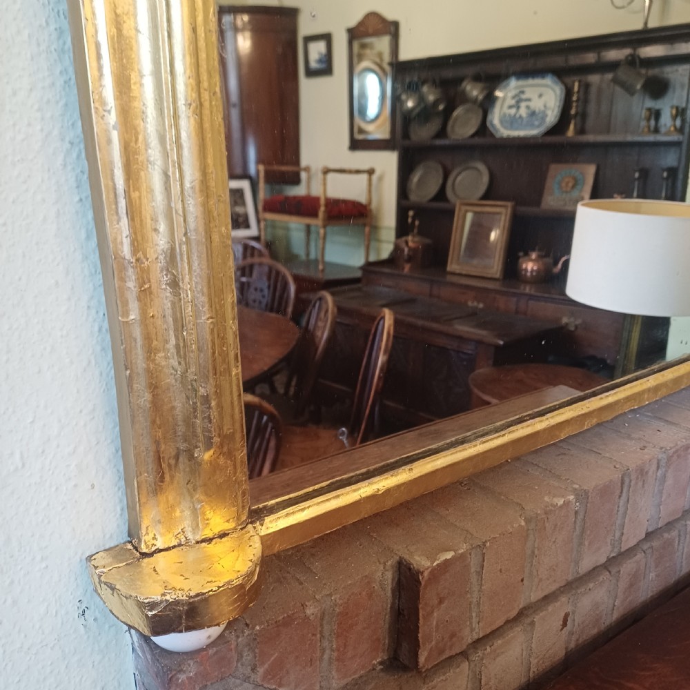 A Victorian giltwood overmantel mirror featuring an arched top frame and moulded gold finish. View VIII