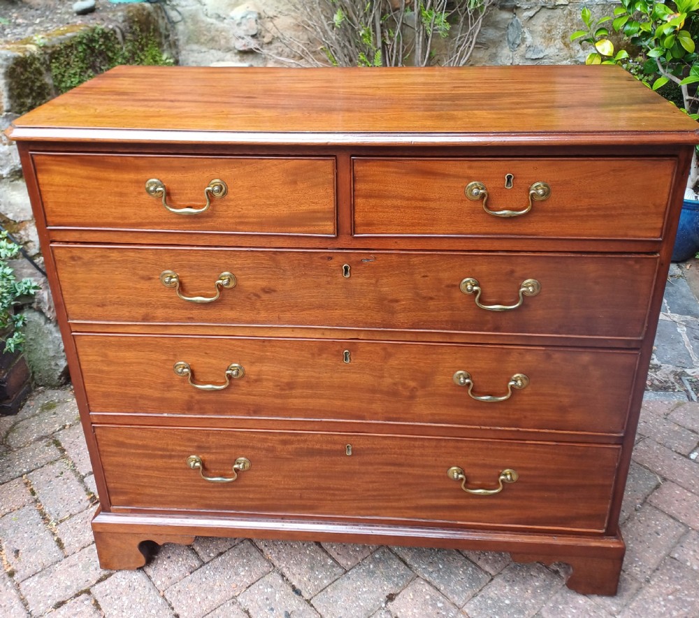 A Georgian mahogany chest of drawers featuring a two-over-three drawer configuration, brass swan-neck handles, keyholes, and bracket feet.
