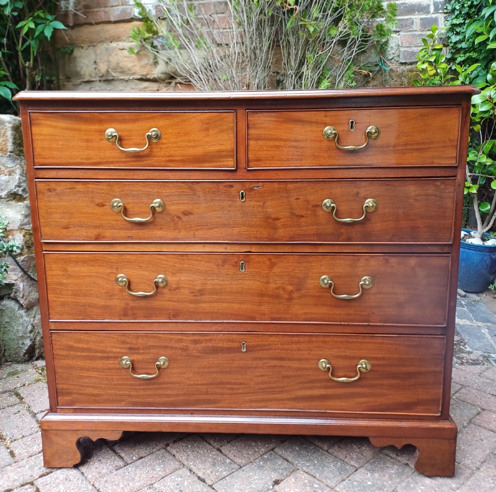 A Georgian mahogany chest of drawers featuring a two-over-three drawer configuration, brass swan-neck handles, keyholes, and bracket feet. View II