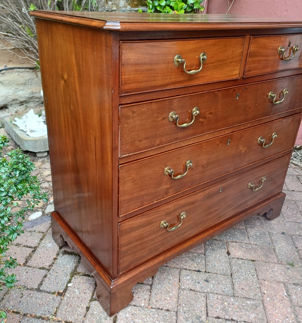 A Georgian mahogany chest of drawers featuring a two-over-three drawer configuration, brass swan-neck handles, keyholes, and bracket feet. View III