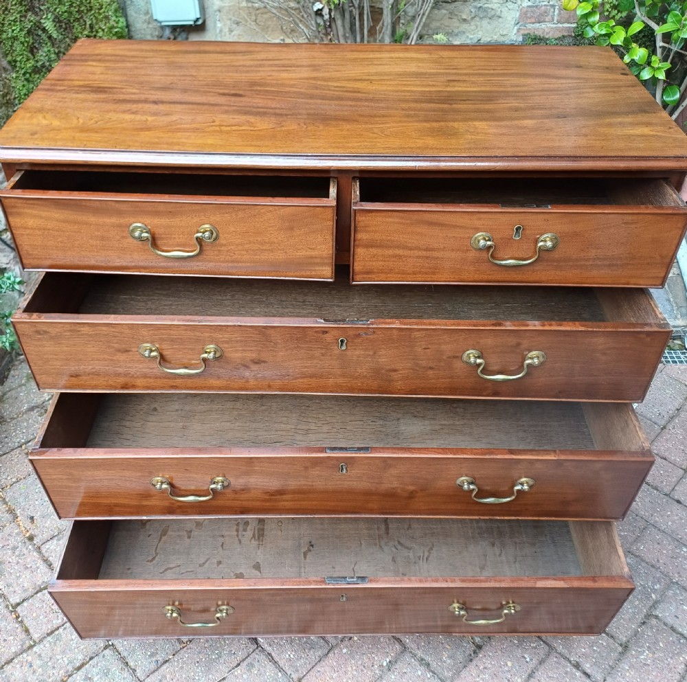 A Georgian mahogany chest of drawers featuring a two-over-three drawer configuration, brass swan-neck handles, keyholes, and bracket feet. View VI