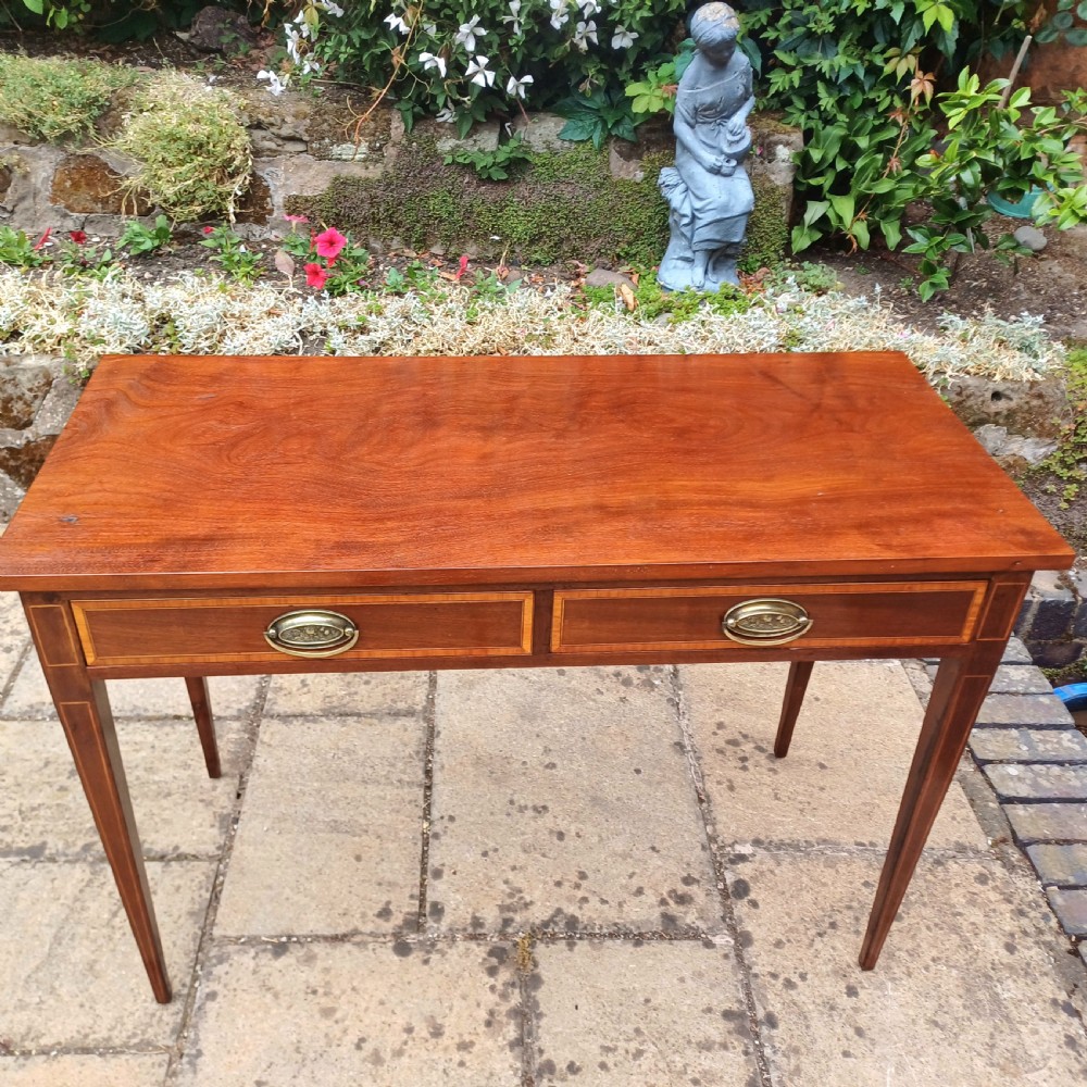 An Edwardian mahogany writing table featuring two inlaid drawers, brass oval drop handles, and slender tapered legs. View II