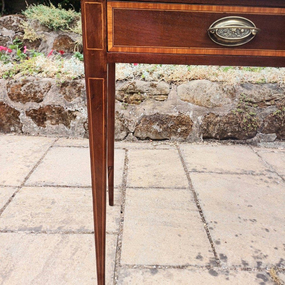 An Edwardian mahogany writing table featuring two inlaid drawers, brass oval drop handles, and slender tapered legs. View VIII
