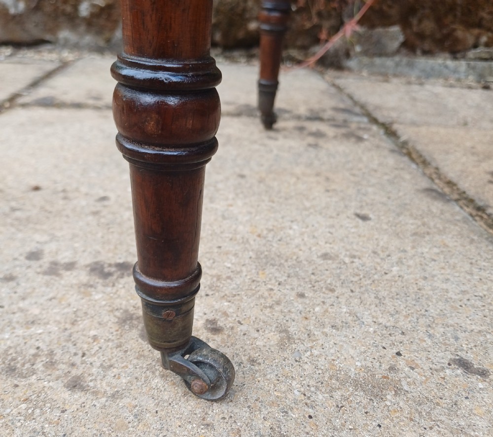 A Regency mahogany miniature Pembroke table featuring two drop leaves, two drawers with brass ring handles, and turned reeded legs on castors. View IX