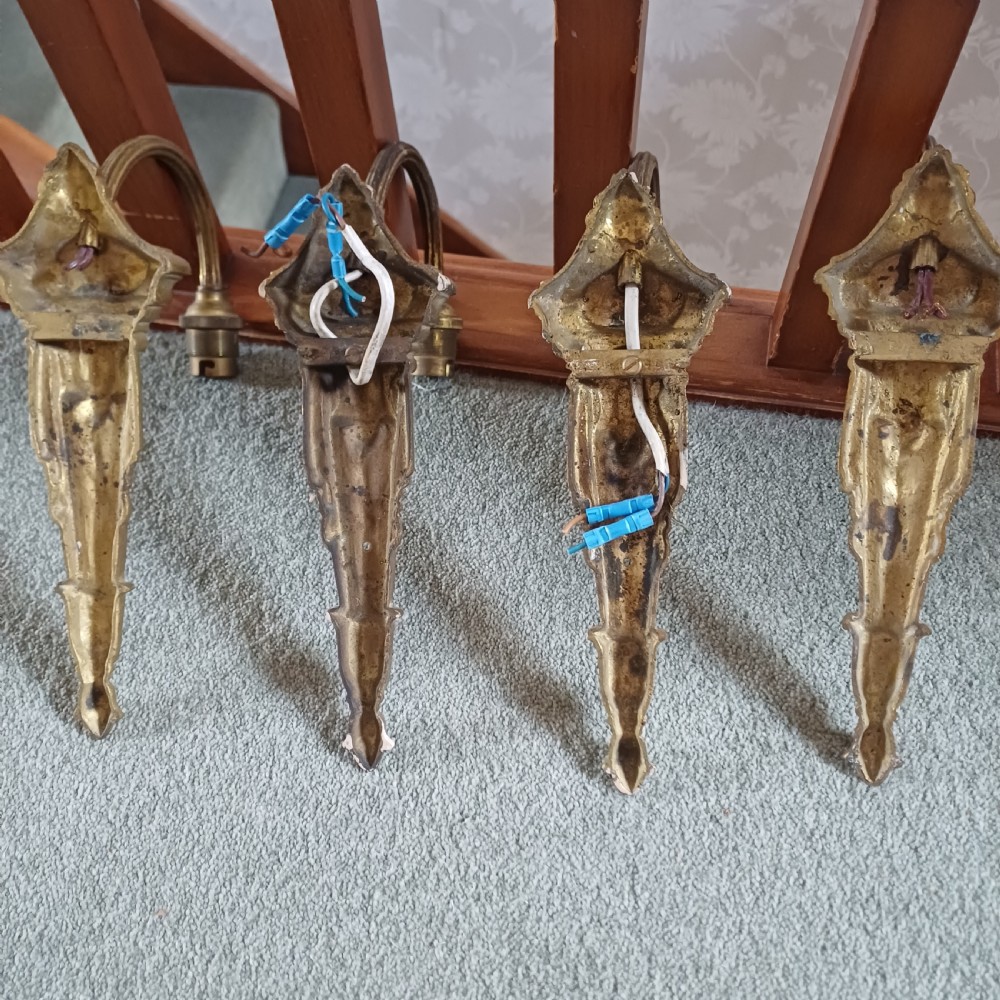 A set of four ornate gilded brass single-arm wall sconces featuring tapered backplates with classical scroll detailing. View IV