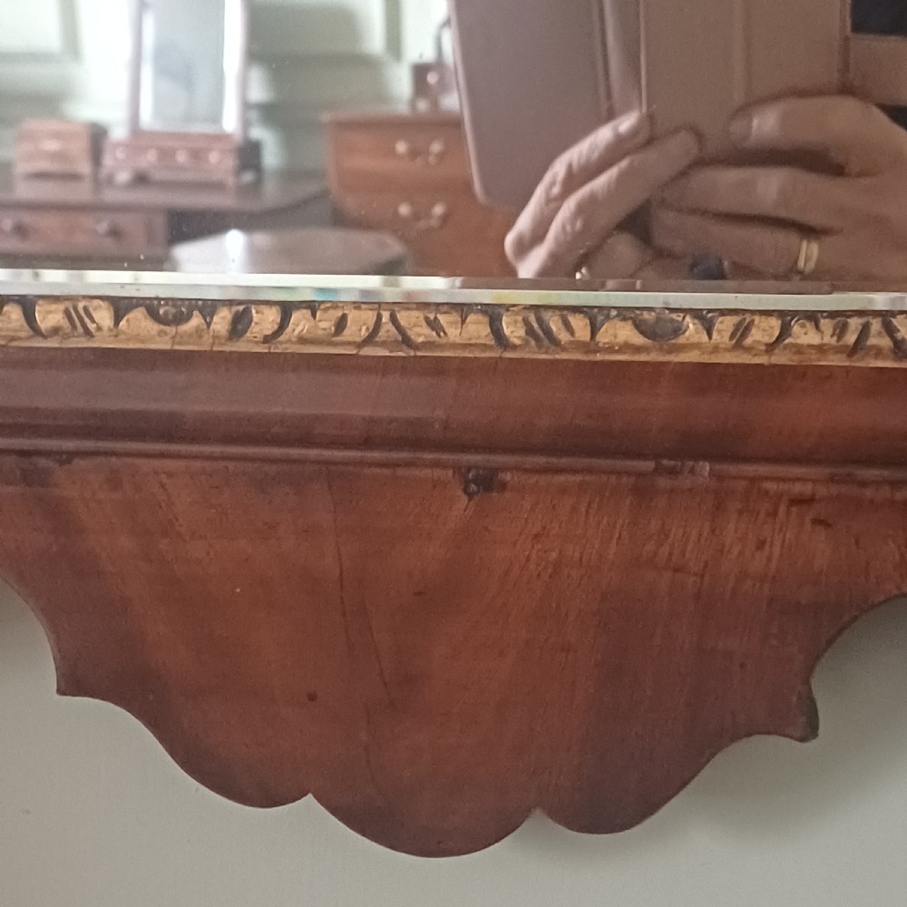 An antique Georgian mahogany wall mirror featuring a scrollwork fretwork frame, a gilded inner slip, and a round carved gilt emblem at the cresting. View III