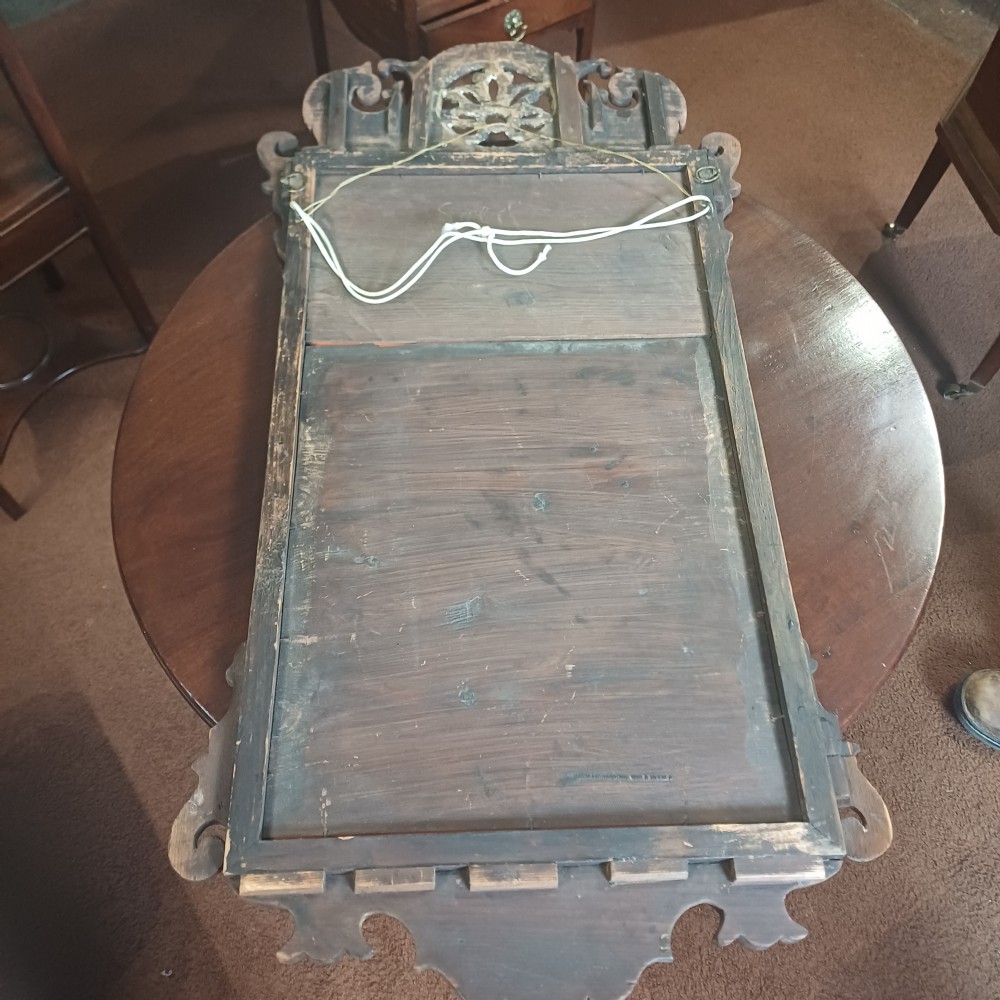 An antique Georgian mahogany wall mirror featuring a scrollwork fretwork frame, a gilded inner slip, and a round carved gilt emblem at the cresting. View VII