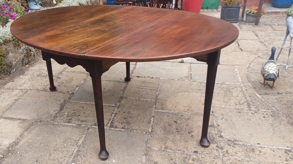 A dark mahogany Georgian drop-leaf dining table with two hinged side leaves resting on tapered legs with pad feet. View VIII
