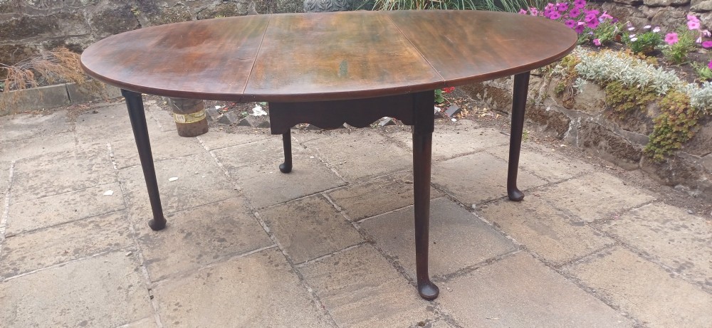 A dark mahogany Georgian drop-leaf dining table with two hinged side leaves resting on tapered legs with pad feet. View IX