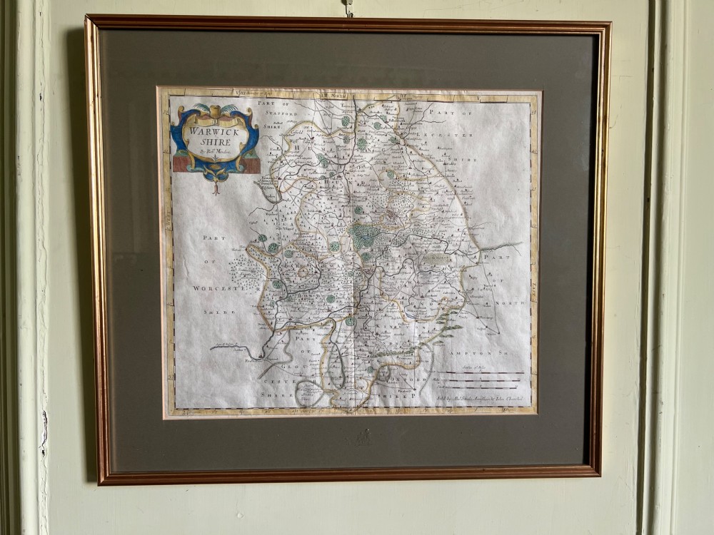 A framed 17th-century hand-coloured map of Warwickshire by Robert Morden set in a wide grey mount with a gilt frame.