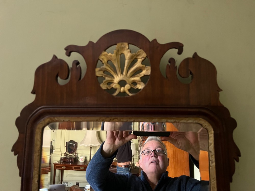 A vertical rectangular wall mirror with a dark mahogany frame, scroll-carved fretwork borders, and a gilded carved crest at the top. View II