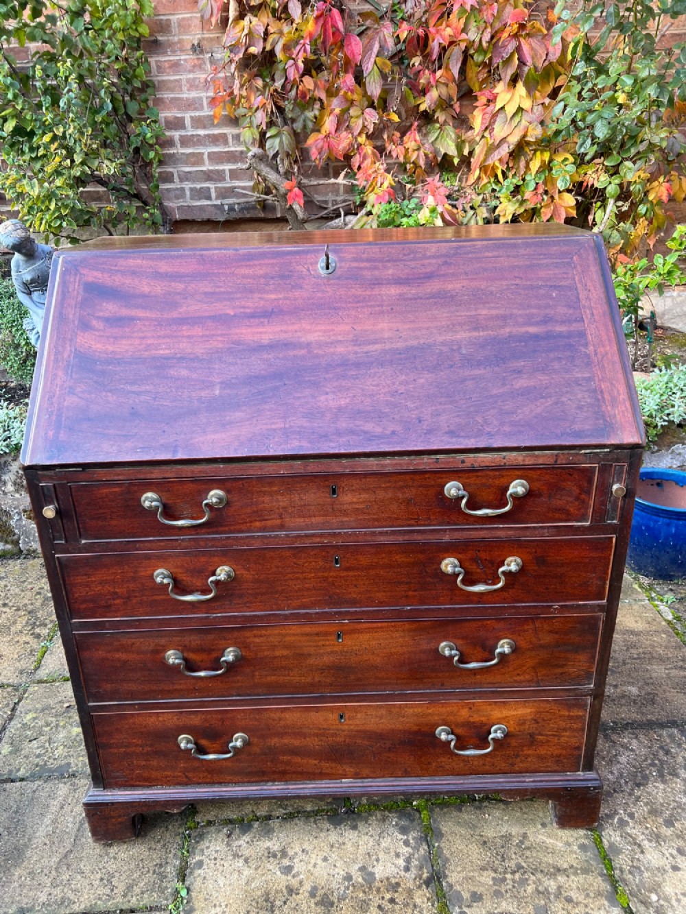 An 18th-century Georgian mahogany bureau with a slant-front writing lid above four long graduated drawers fitted with brass swan-neck handles.