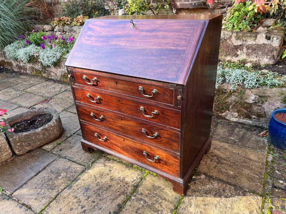 An 18th-century Georgian mahogany bureau with a slant-front writing lid above four long graduated drawers fitted with brass swan-neck handles. View II