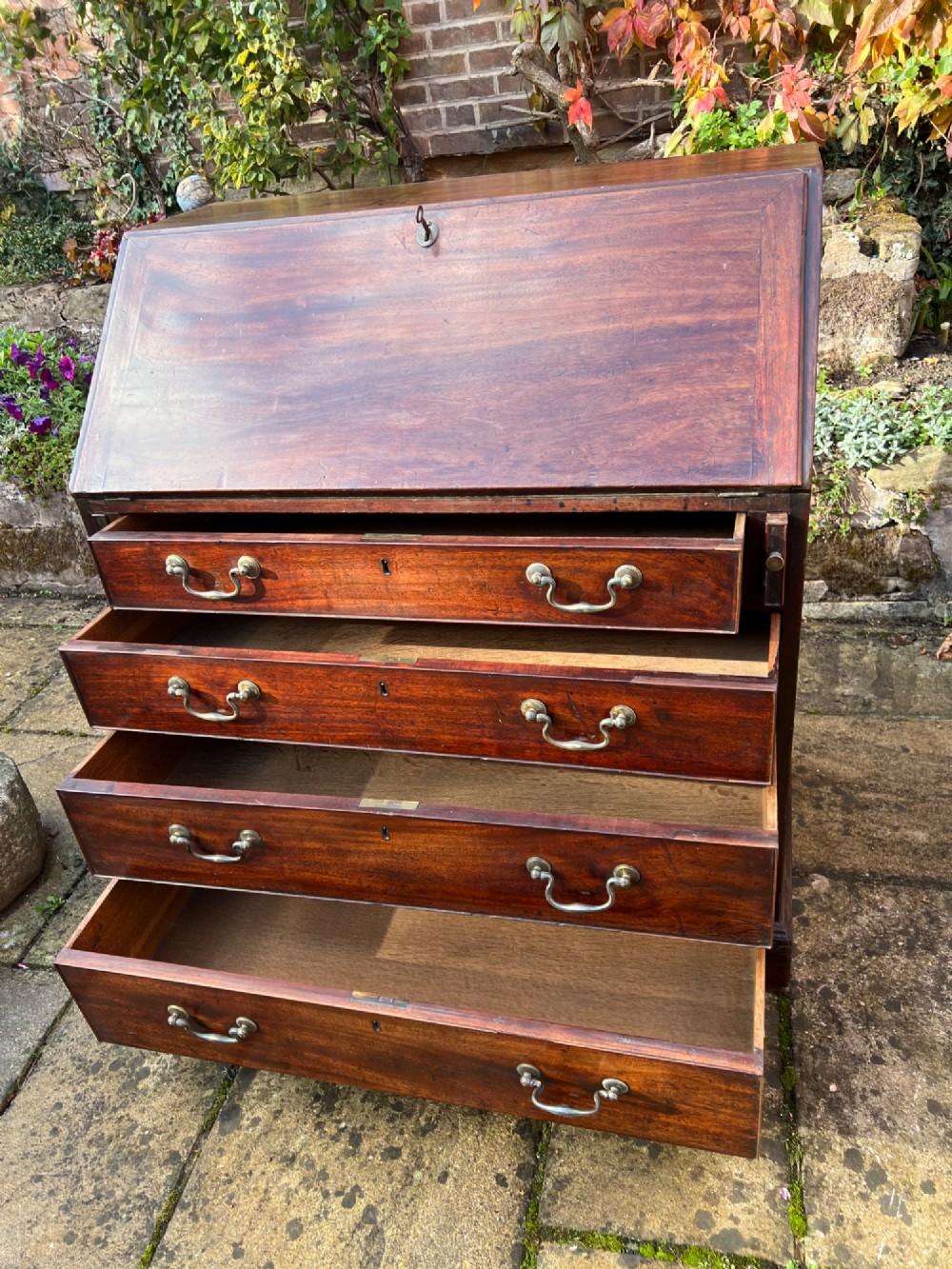 An 18th-century Georgian mahogany bureau with a slant-front writing lid above four long graduated drawers fitted with brass swan-neck handles. View V