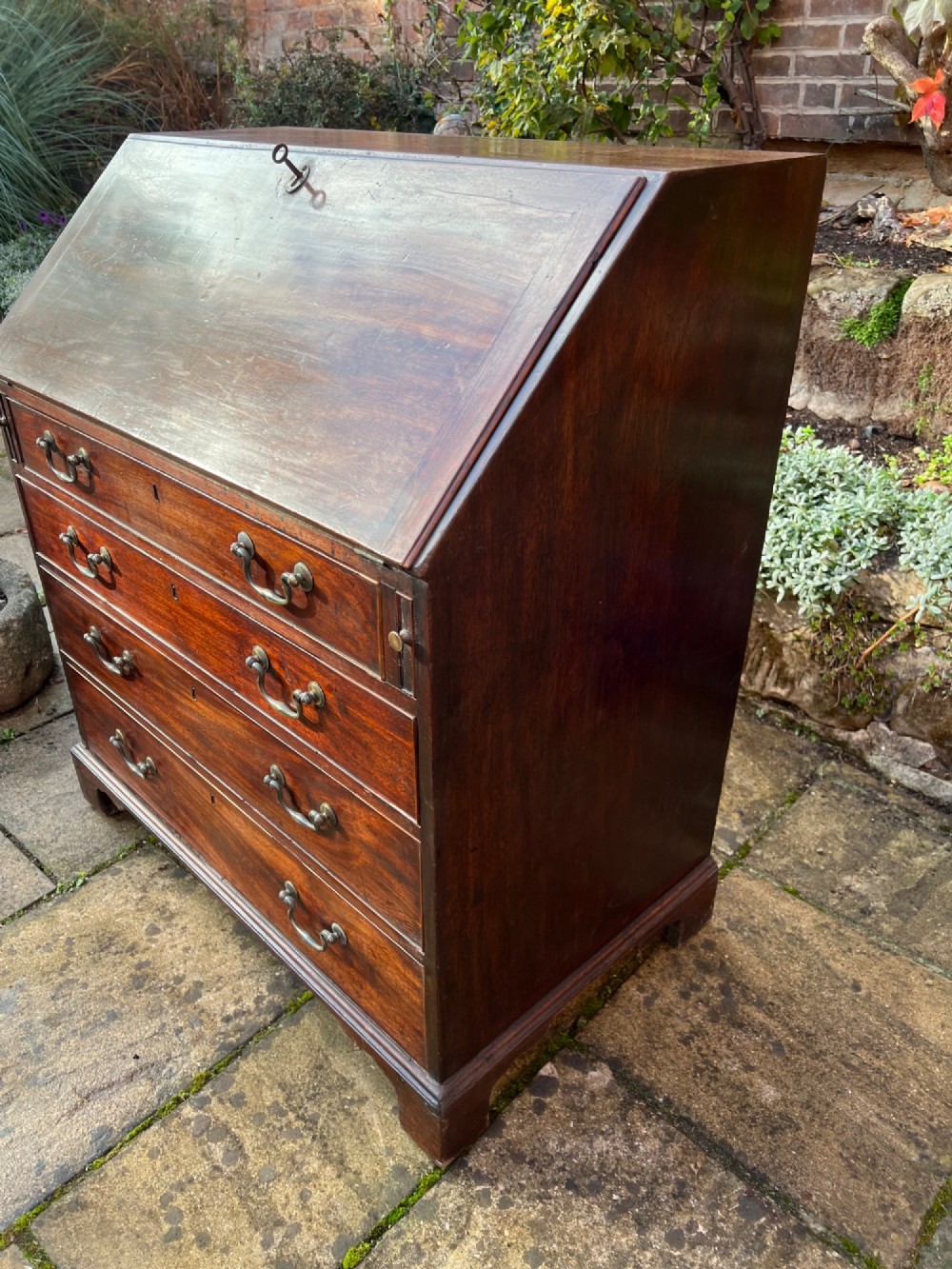 An 18th-century Georgian mahogany bureau with a slant-front writing lid above four long graduated drawers fitted with brass swan-neck handles. View VI
