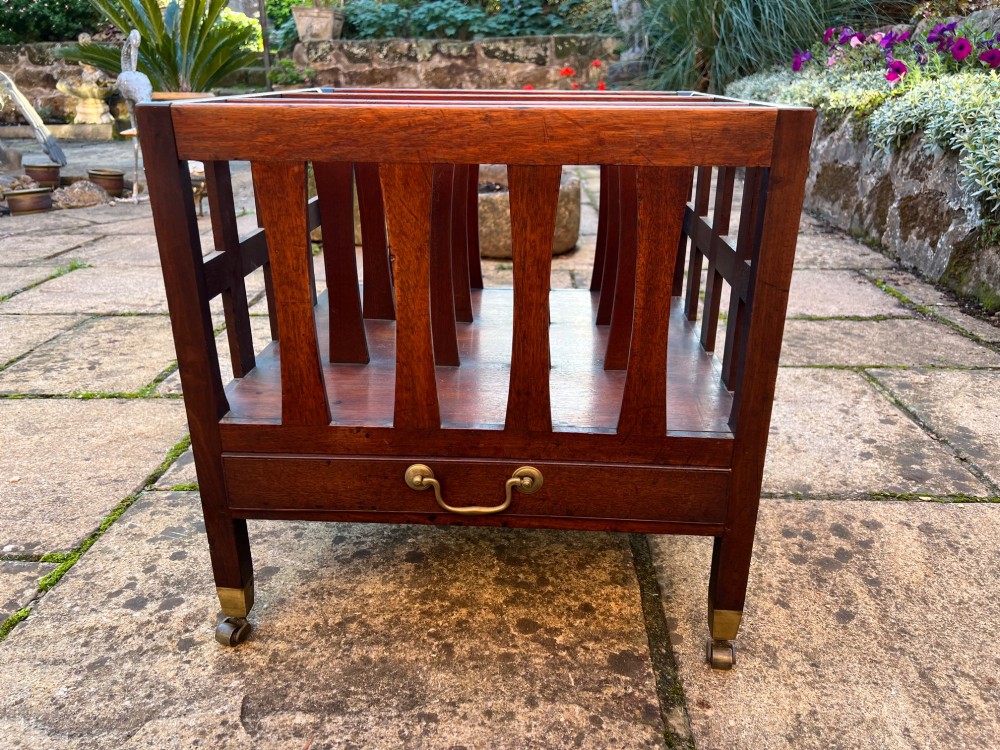 An eighteenth-century mahogany Canterbury featuring slatted vertical dividers, a single lower drawer with a brass handle, and four legs with brass castors.