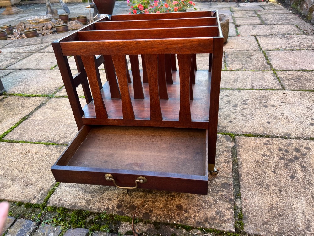 An eighteenth-century mahogany Canterbury featuring slatted vertical dividers, a single lower drawer with a brass handle, and four legs with brass castors. View IV