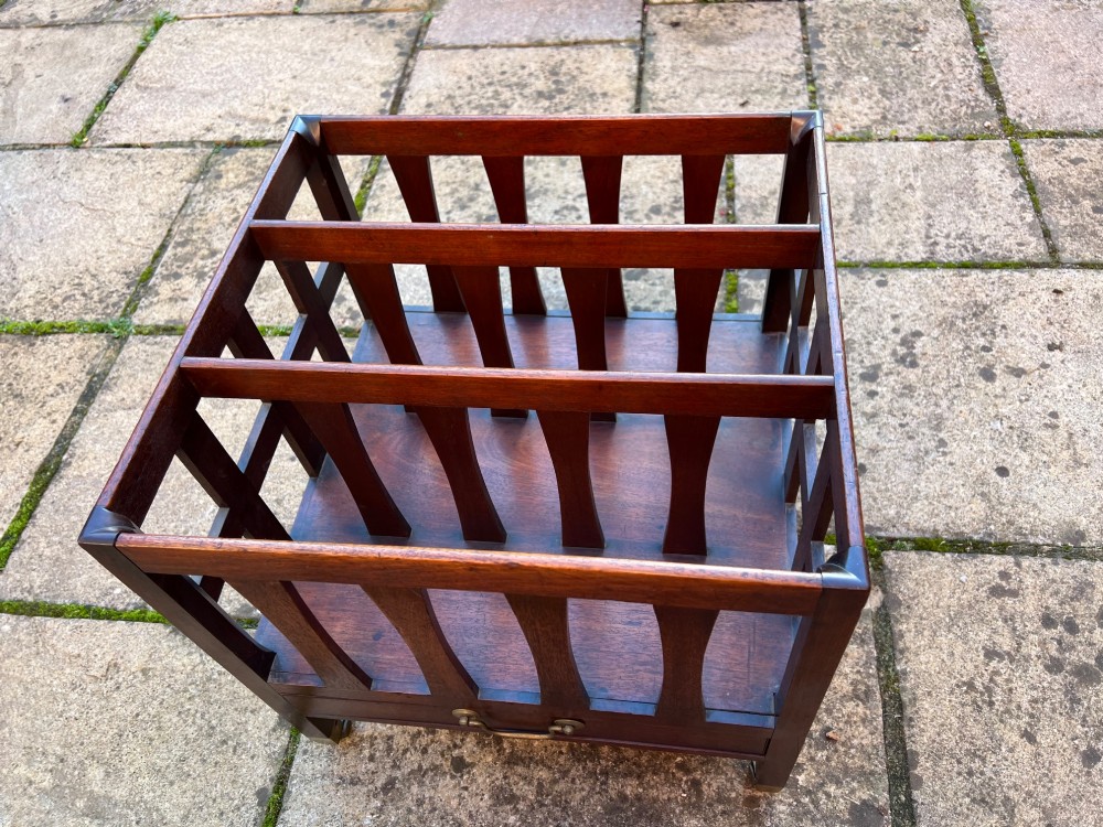 An eighteenth-century mahogany Canterbury featuring slatted vertical dividers, a single lower drawer with a brass handle, and four legs with brass castors. View V