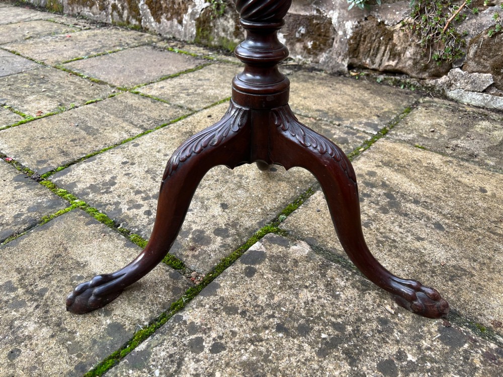 An eighteenth-century circular mahogany tripod table featuring a turned fluted column, acanthus carved cabriole legs, and claw-and-ball feet. View II