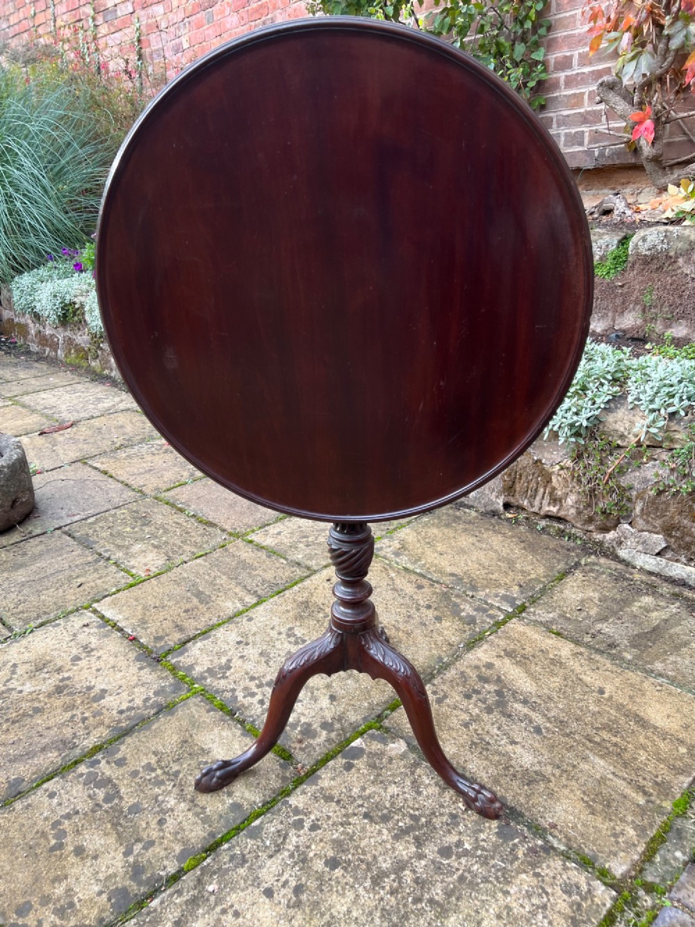 An eighteenth-century circular mahogany tripod table featuring a turned fluted column, acanthus carved cabriole legs, and claw-and-ball feet. View IV
