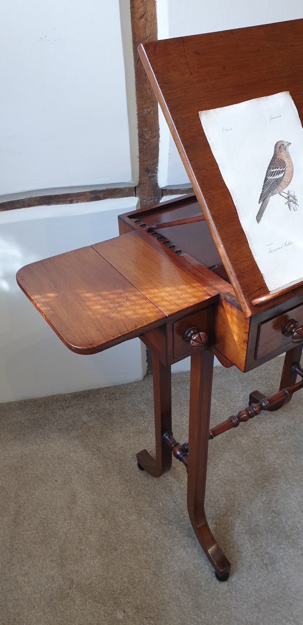 An antique mahogany occasional table featuring a ratcheted reading top, pull-out side slides, a drawer with wooden knobs, and splayed legs with a turned stretcher. View VII