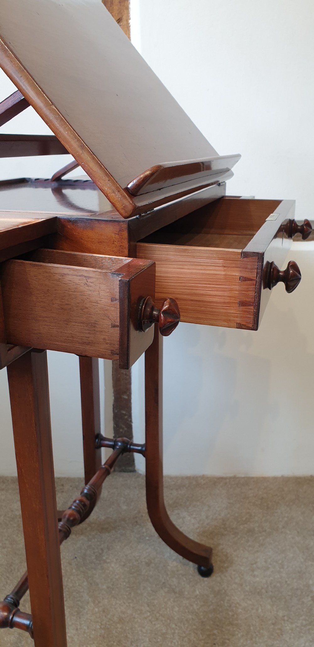 An antique mahogany occasional table featuring a ratcheted reading top, pull-out side slides, a drawer with wooden knobs, and splayed legs with a turned stretcher. View VIII