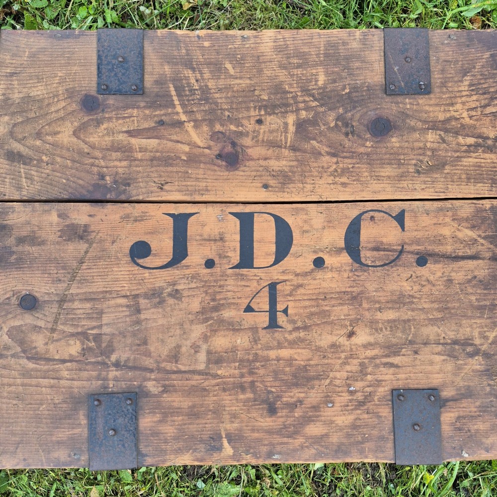 A pair of rectangular natural pine chests featuring black iron corner brackets, metal straps, keyhole escutcheons, and black stencilled text on the lids. View IV