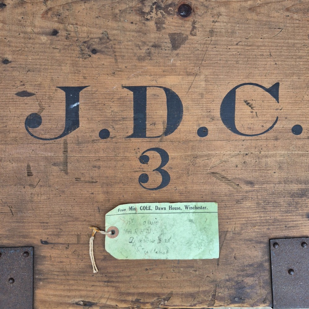 A pair of rectangular natural pine chests featuring black iron corner brackets, metal straps, keyhole escutcheons, and black stencilled text on the lids. View VIII