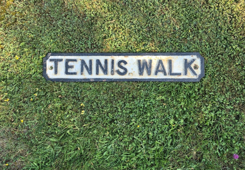 A rectangular 1920s cast iron street sign featuring embossed black lettering spelling TENNIS WALK on a weathered off-white background with a black border. View II