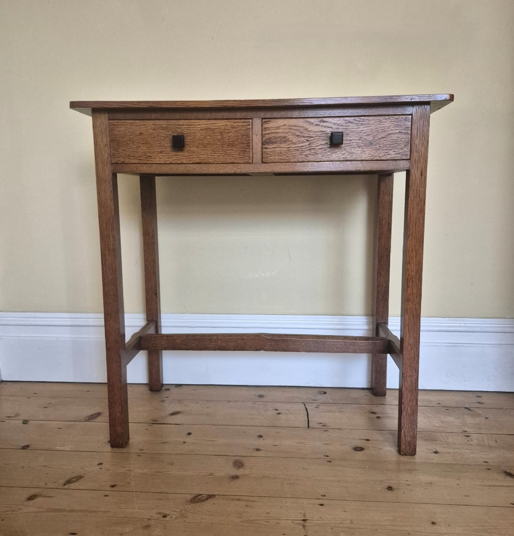 A medium brown antique oak side table featuring two drawers with dark square knobs, straight square legs, and an H-stretcher base. View II