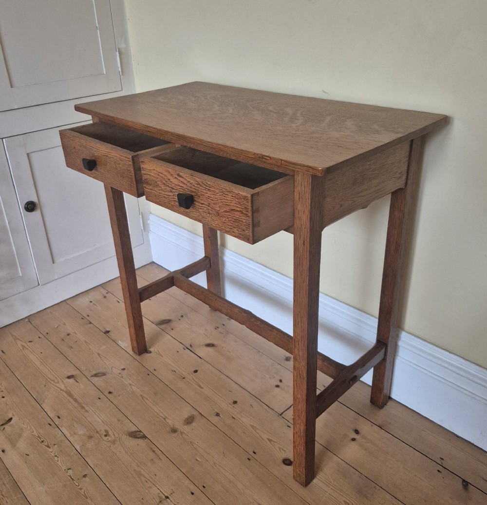 A medium brown antique oak side table featuring two drawers with dark square knobs, straight square legs, and an H-stretcher base. View IV