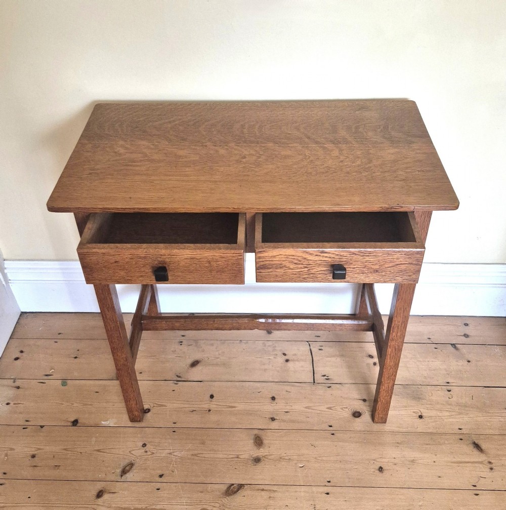 A medium brown antique oak side table featuring two drawers with dark square knobs, straight square legs, and an H-stretcher base. View V