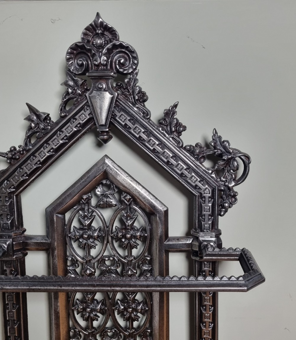A Victorian cast iron stick stand featuring a pierced Gothic arch design, retention bar, and a rectangular drip tray base. View III
