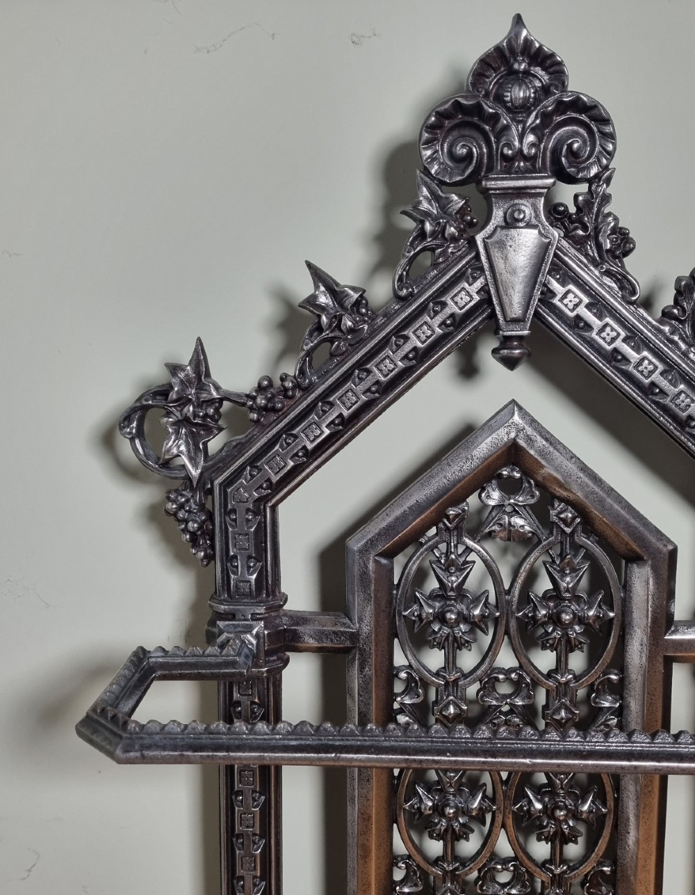 A Victorian cast iron stick stand featuring a pierced Gothic arch design, retention bar, and a rectangular drip tray base. View IV