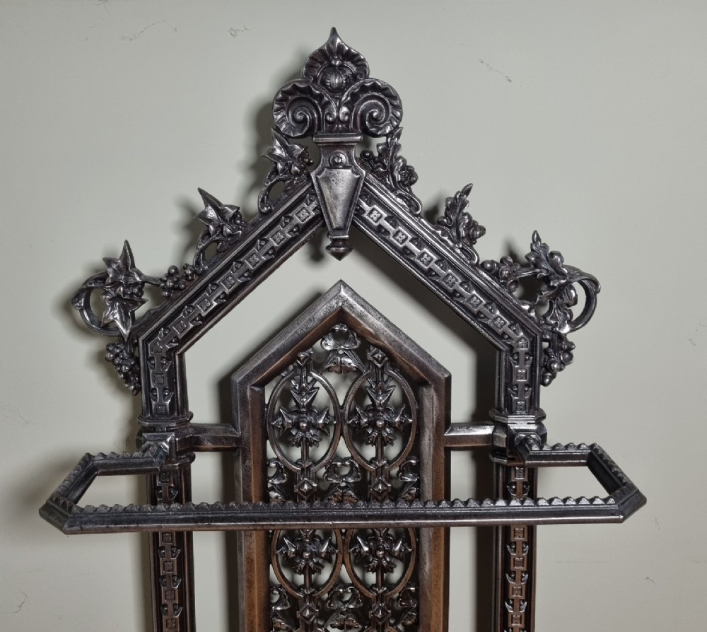 A Victorian cast iron stick stand featuring a pierced Gothic arch design, retention bar, and a rectangular drip tray base. View VIII