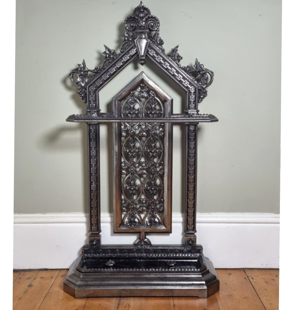 A Victorian cast iron stick stand featuring a pierced Gothic arch design, retention bar, and a rectangular drip tray base. View II