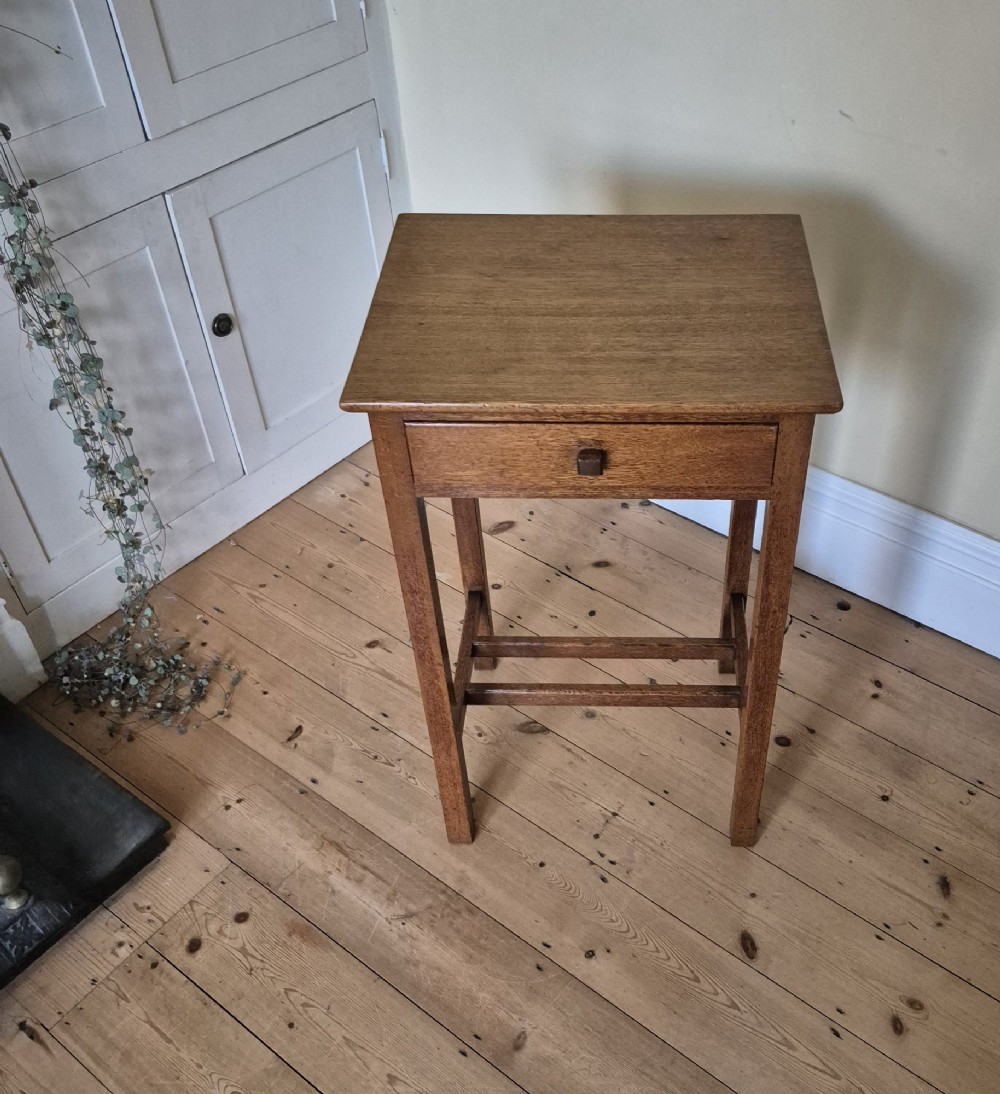 A tall rectangular oak side table featuring a single drawer with a square wooden knob and straight legs connected by a lower stretcher base. View IV