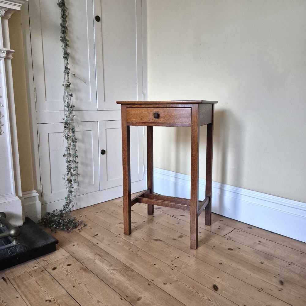 A tall rectangular oak side table featuring a single drawer with a square wooden knob and straight legs connected by a lower stretcher base. View II