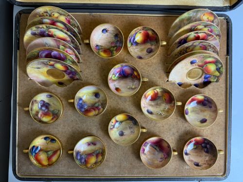 fig 1. An open fitted presentation case containing twelve hand-painted porcelain demitasse coffee cups and saucers decorated with fruit motifs and gilded interiors.