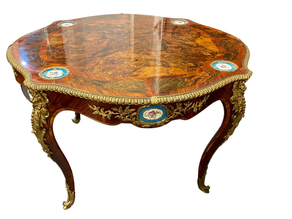 A French 1880 burr walnut centre table with cabriole legs, gilt-bronze mounts, and inset turquoise porcelain plaques.