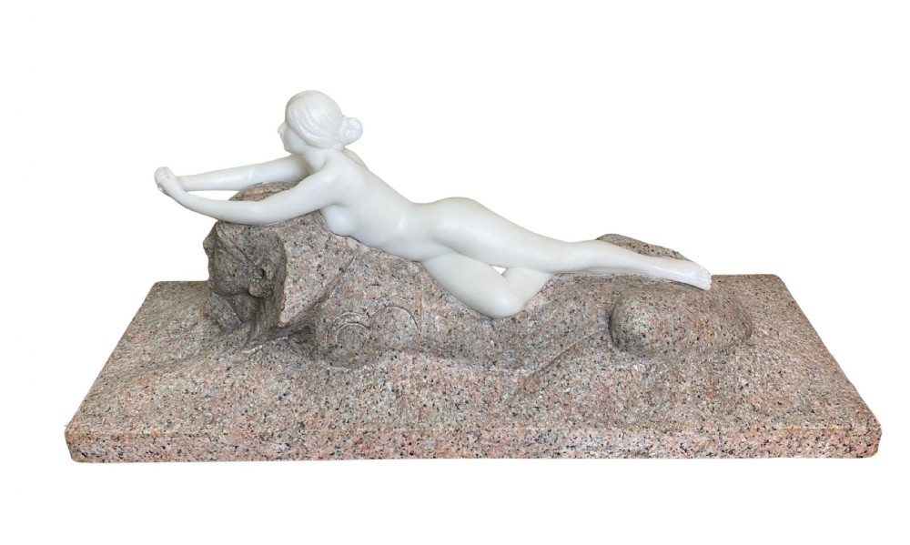 An Art Deco white marble carving of a reclining female nude resting on top of a carved pink granite sphinx base.
